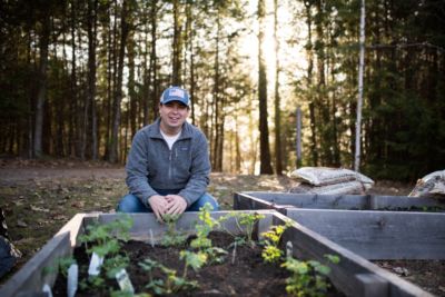 Sustainability Advances At Saint Joseph’s With First Bee Campus Certification In Maine 1 student kneeling at raised bed of pollinator garden which was a sustainability project