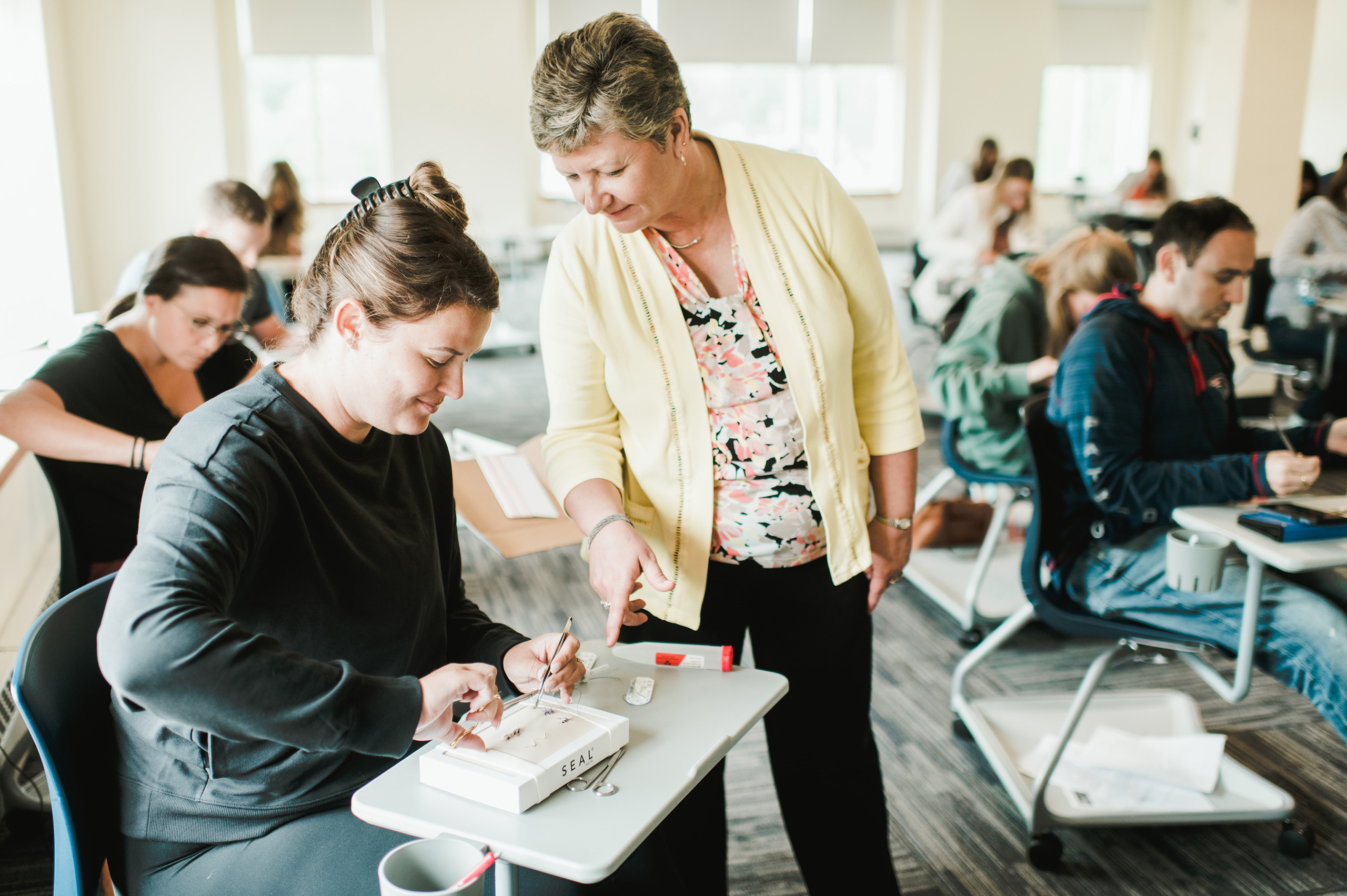 Nursing professor works one on one with nursing student in classroom skills lab